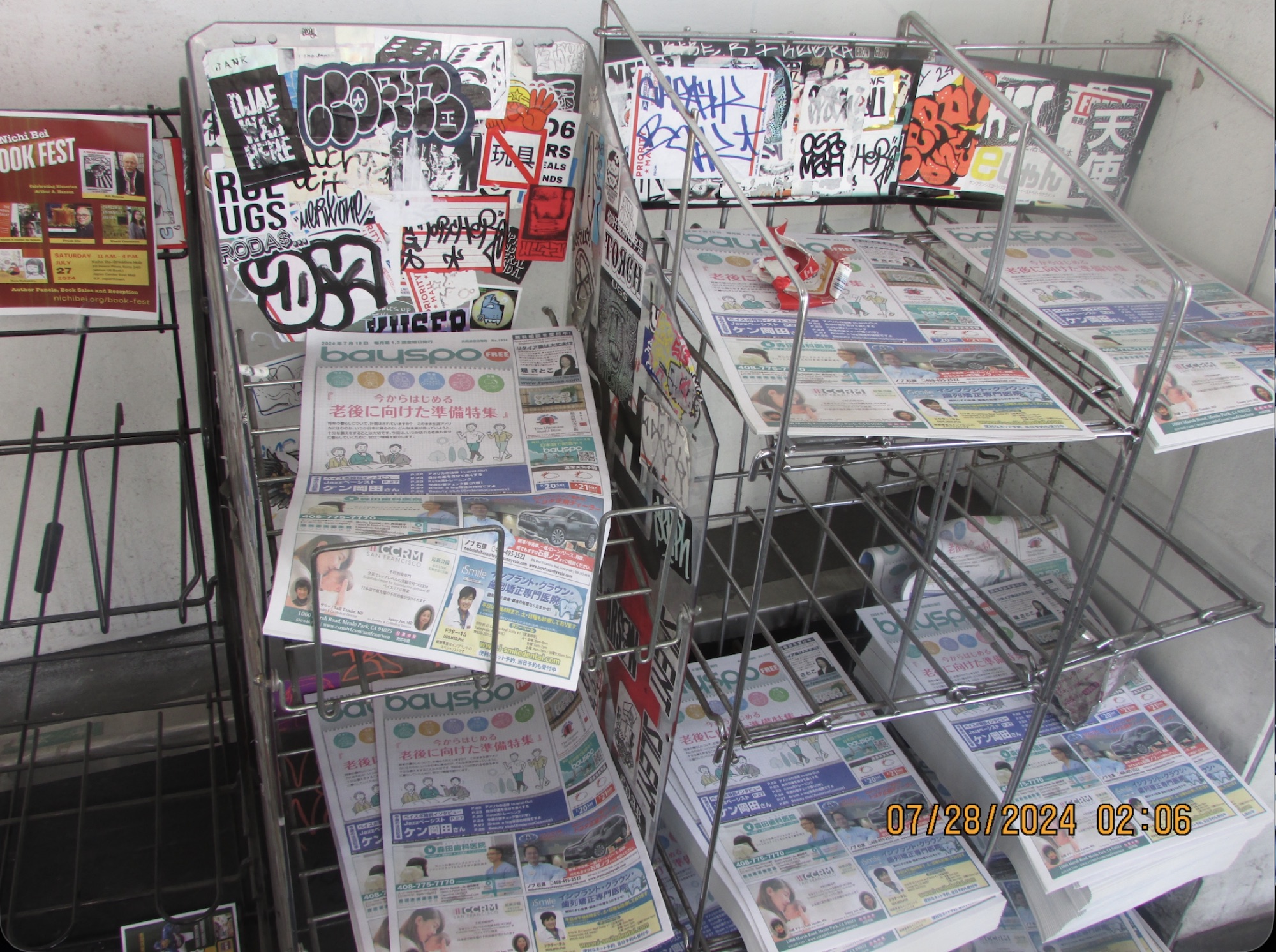 A rack filled with magazines and printed matter, covered in stickers and marker tags.